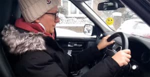 Profile view of a female sitting at the driving wheel of a