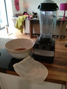Equipment to make almond milk: blender, bowl of soaking almonds and a nut bag.