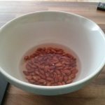 A bowl with almonds saoking in water.