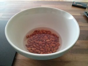 A bowl with almonds saoking in water.