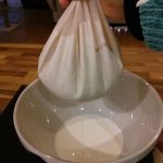 Bowl on kitchen surface with nut bag filled with almond nilk ready to squeeze.